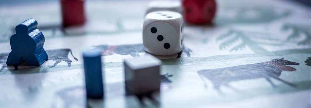 Dice and wooden game pieces on an “antique” game board.